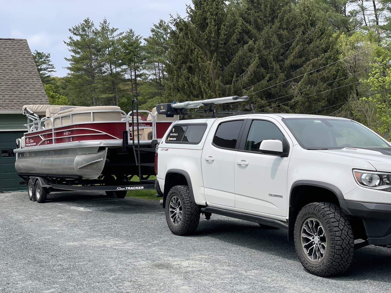 red and white pontoon boat hitched to a white chevrolet truck with a white truck cap