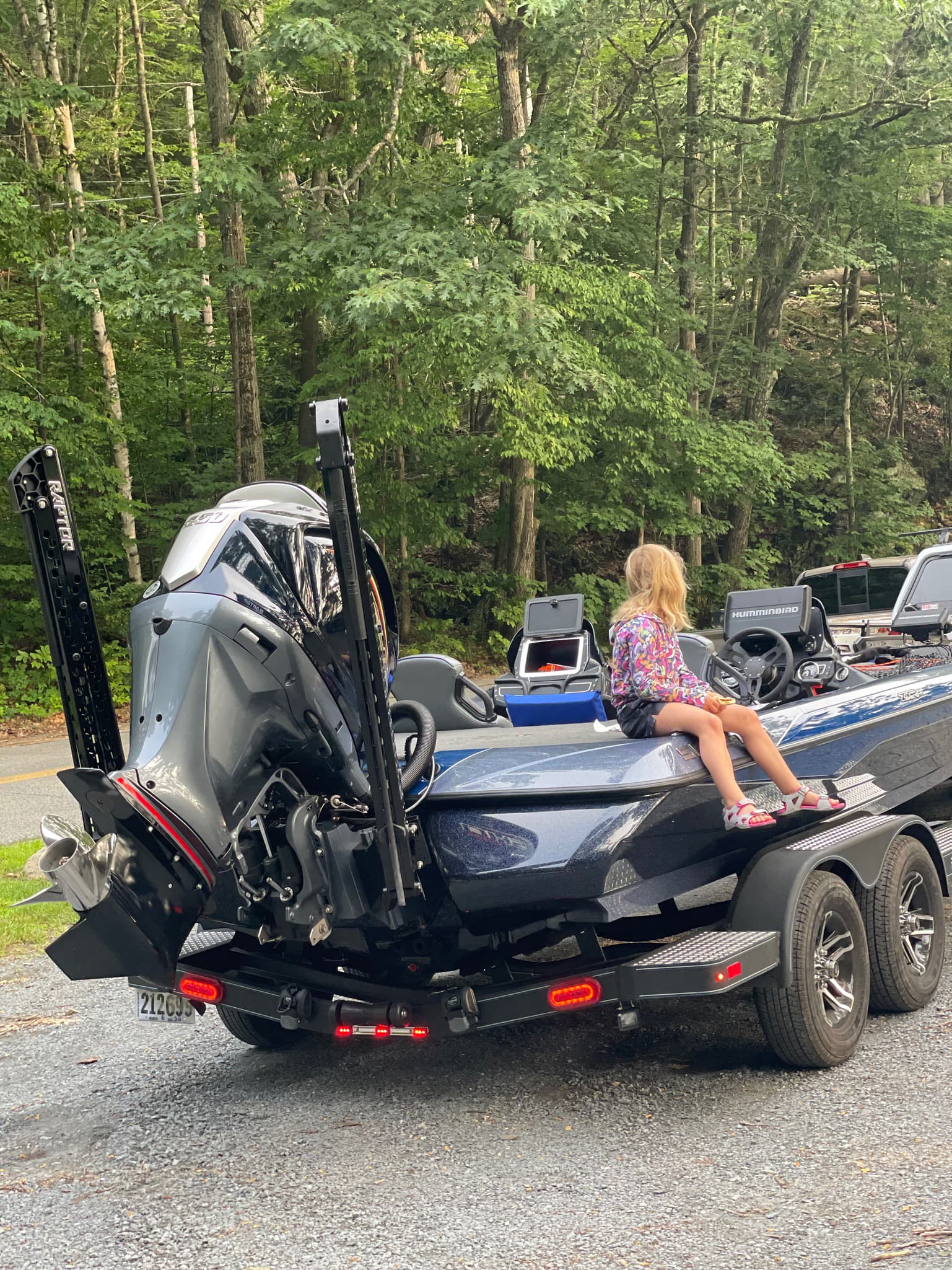 Girl sitting on end of blue boat while parked on land