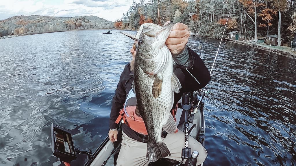 Michael Blatt holding fish out of water in a kayak while looking away