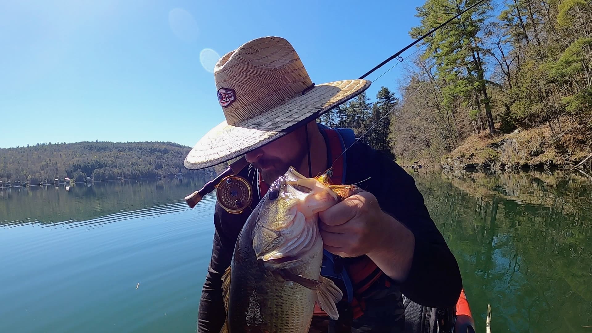 Angler casting fly rod on calm water during fly fishing expedition