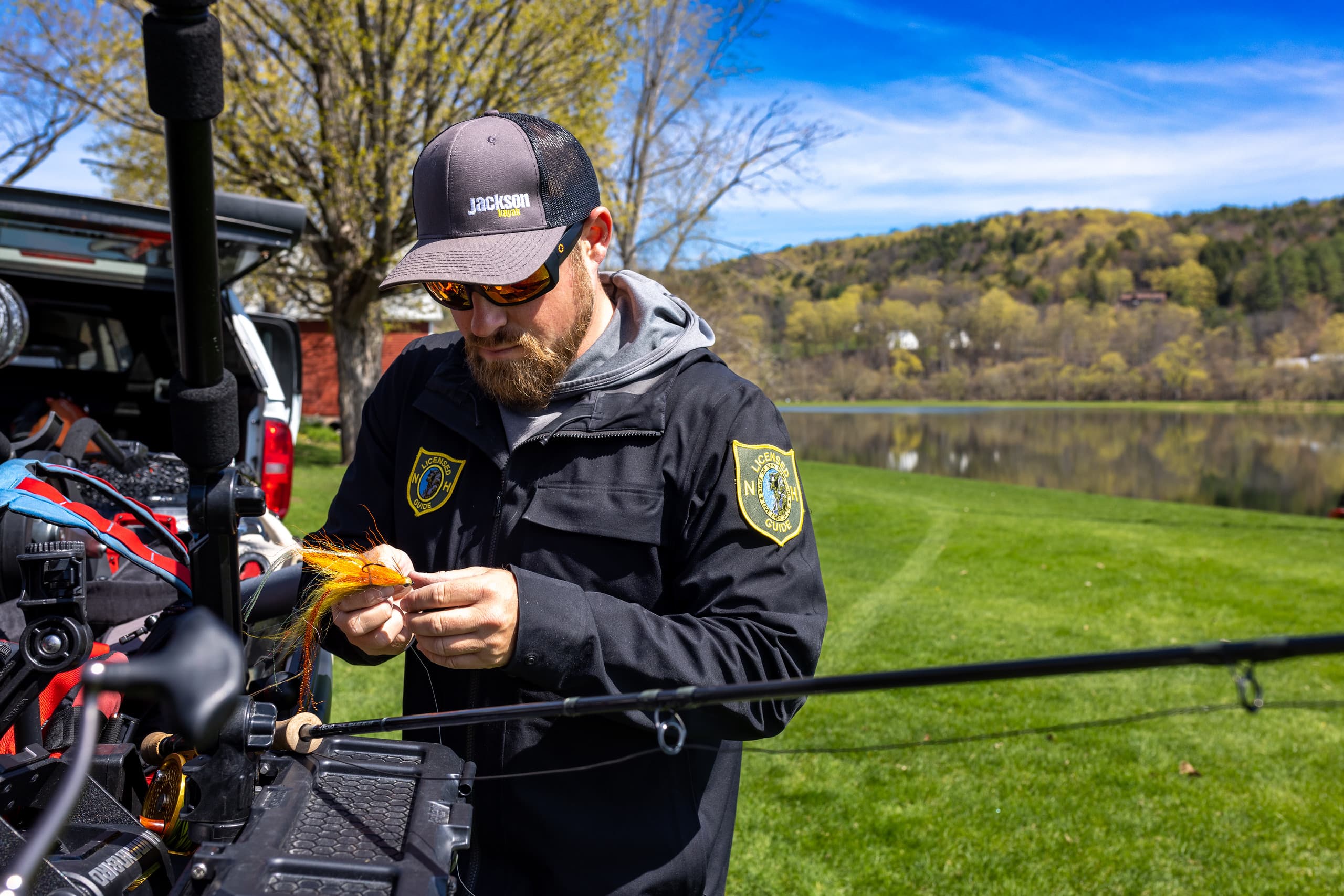 man wearing hat and sunglasses tying bait onto fishing line