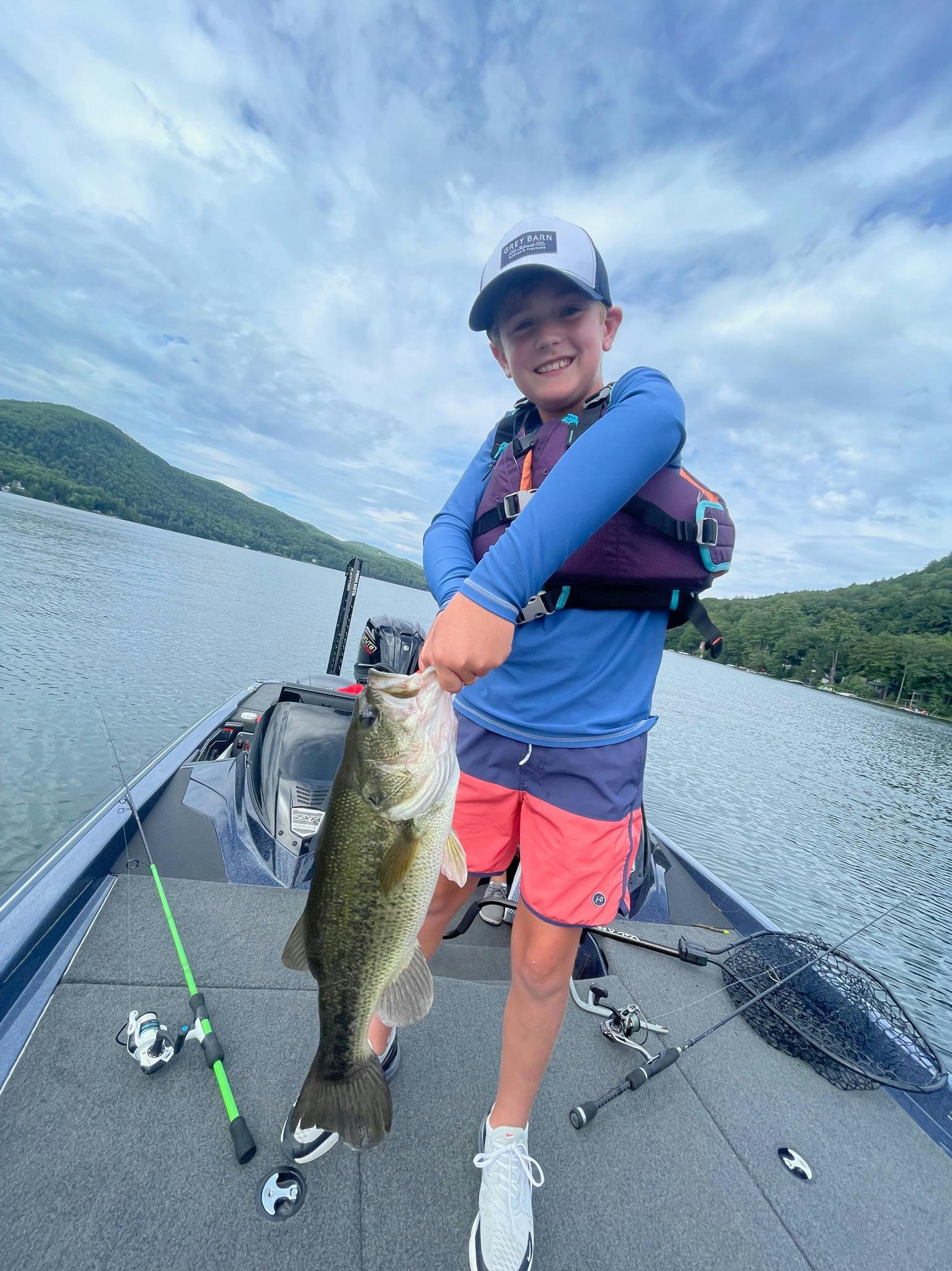 boy in blue shirt and pink shorts holding largemouth bass