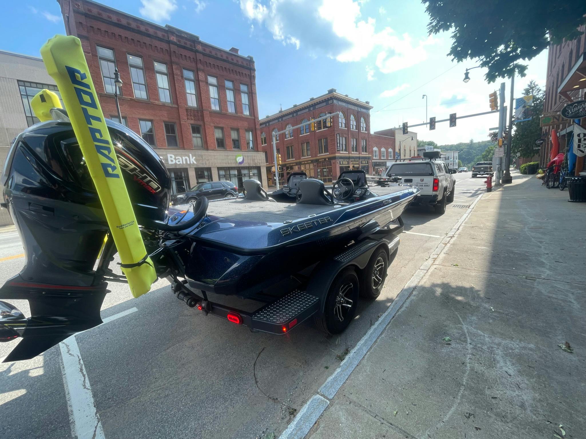 blue boat sitting in city parking space while hitched to white truck