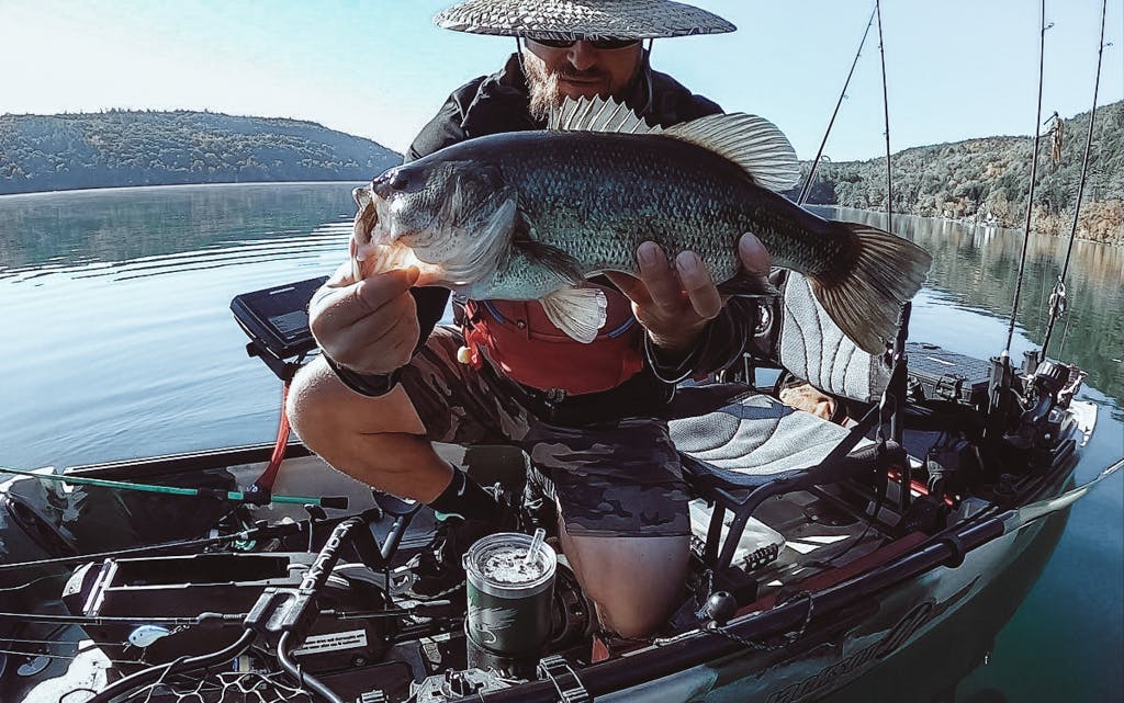 Michael Blatt holding fish out of water in a kayak while looking forward